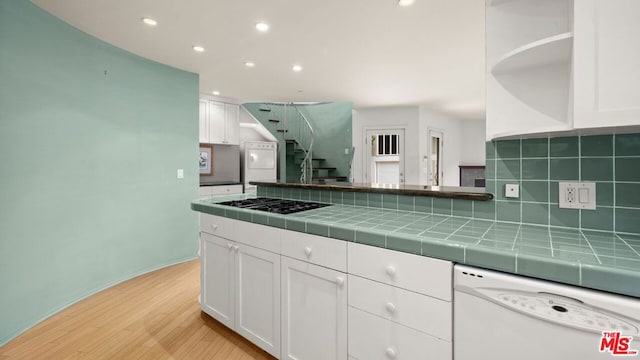 kitchen featuring tile countertops, light hardwood / wood-style floors, gas cooktop, dishwasher, and white cabinets