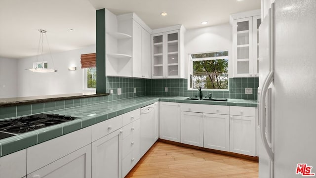 kitchen with white appliances, white cabinets, tile countertops, and hanging light fixtures