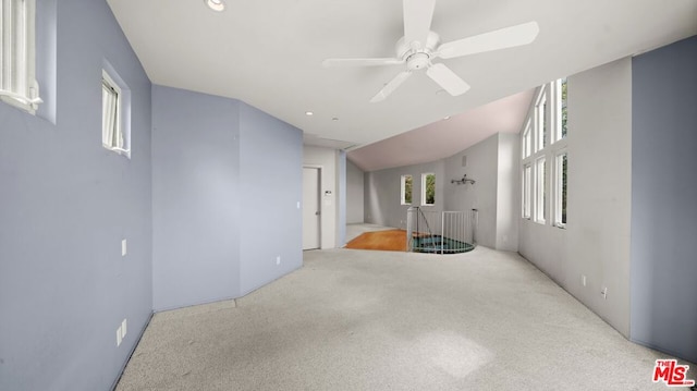 empty room with ceiling fan, lofted ceiling, and light colored carpet