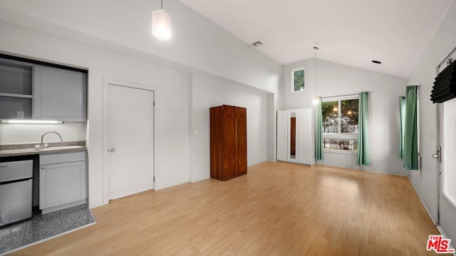 unfurnished living room featuring sink, lofted ceiling, and light wood-type flooring