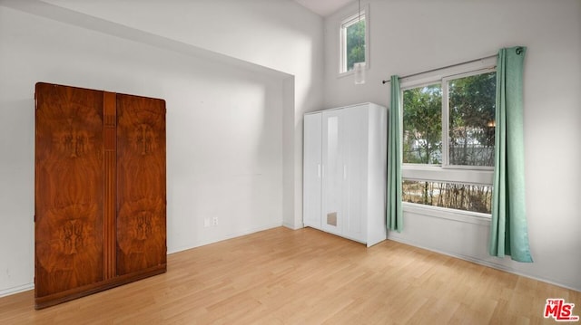 empty room with light hardwood / wood-style flooring and lofted ceiling