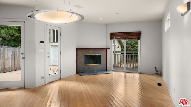 unfurnished living room featuring a tiled fireplace and light hardwood / wood-style flooring