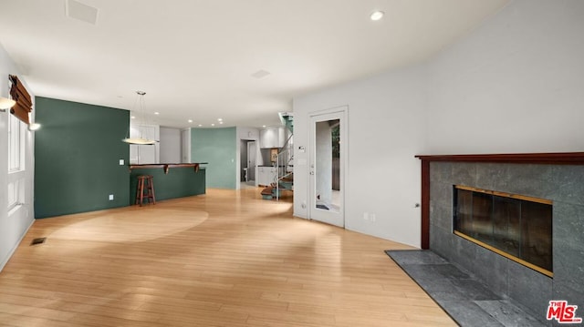 living room with a high end fireplace and light hardwood / wood-style floors