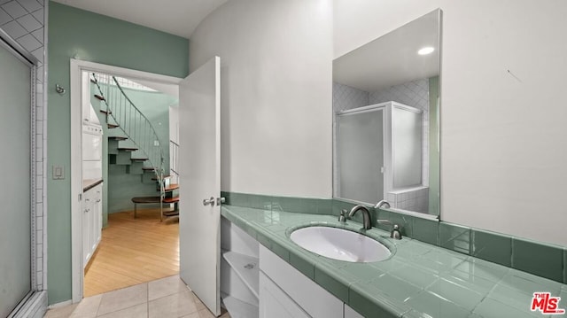 bathroom with an enclosed shower, vanity, and tile patterned flooring