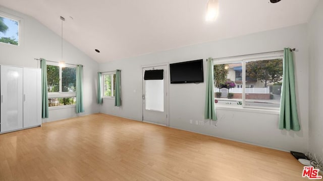 empty room with light hardwood / wood-style floors and high vaulted ceiling