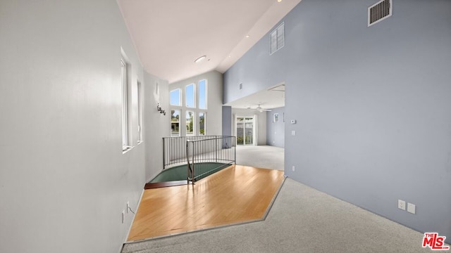 hall featuring a towering ceiling and carpet flooring