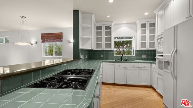 kitchen featuring white appliances, white cabinetry, sink, hanging light fixtures, and tile countertops