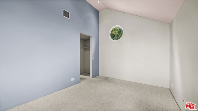 unfurnished room featuring light carpet and high vaulted ceiling