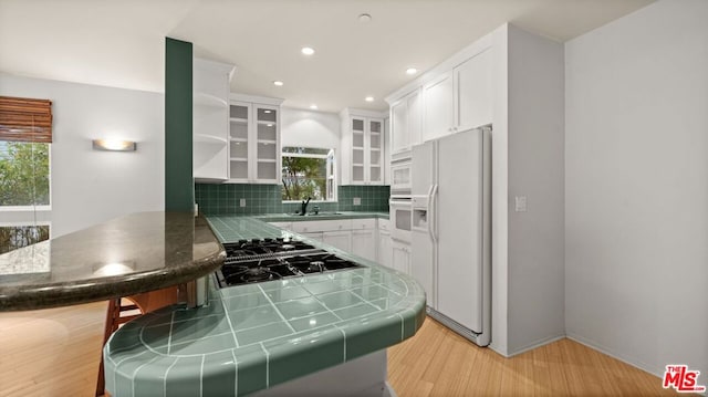 kitchen featuring white appliances, white cabinetry, light hardwood / wood-style floors, sink, and kitchen peninsula