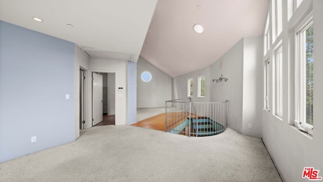 hallway with carpet, vaulted ceiling, and plenty of natural light