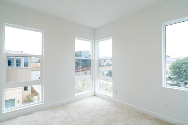 spare room featuring light colored carpet and a fireplace