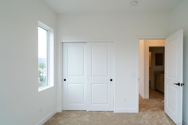 unfurnished bedroom with a closet and light colored carpet