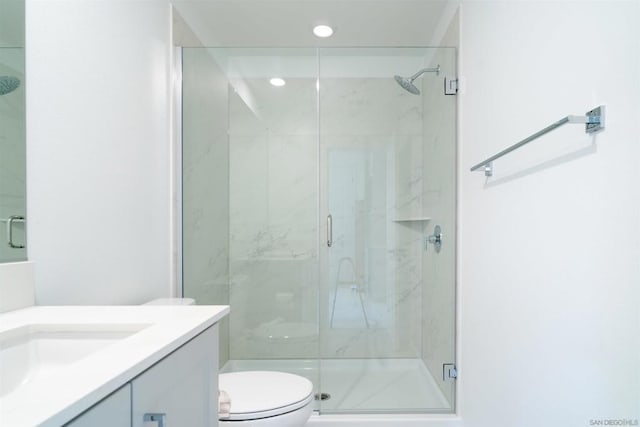 bathroom with toilet, vanity, and a shower with shower door