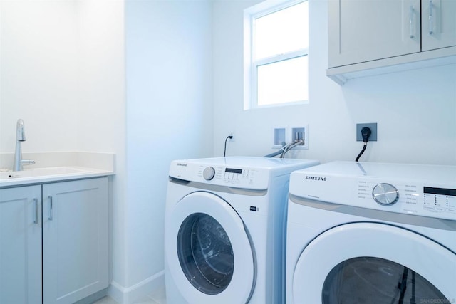 clothes washing area with cabinets, sink, and washing machine and clothes dryer