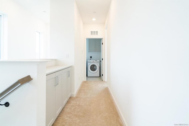 corridor featuring light colored carpet and washer / dryer