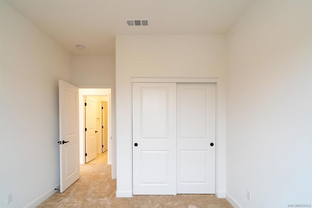 unfurnished bedroom featuring light carpet and a closet