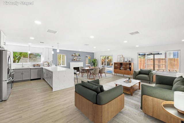 living room with ceiling fan, light wood-type flooring, plenty of natural light, and sink