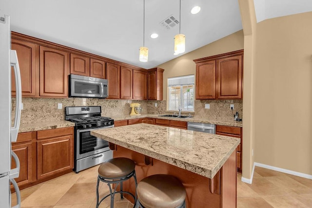 kitchen featuring appliances with stainless steel finishes, lofted ceiling, a kitchen island, a breakfast bar, and sink