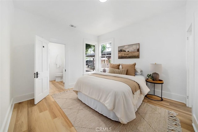 bedroom featuring hardwood / wood-style flooring and ensuite bathroom