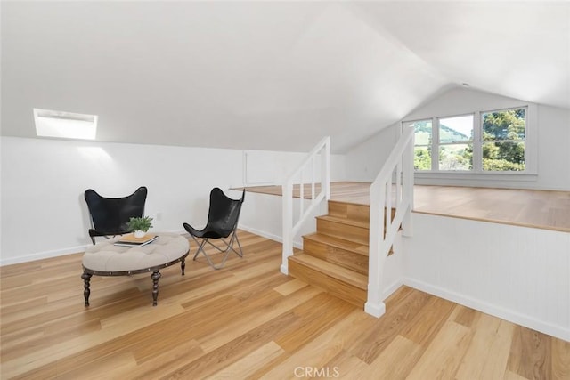 sitting room with vaulted ceiling with skylight and hardwood / wood-style flooring