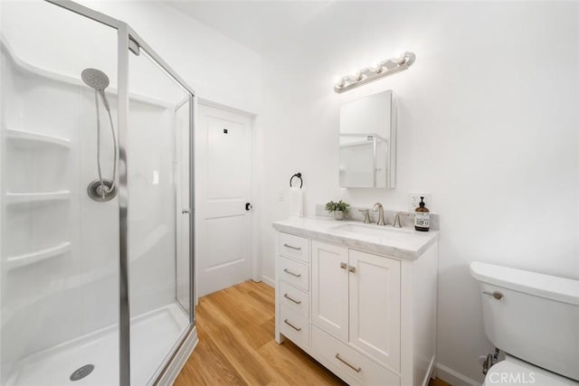 bathroom with hardwood / wood-style floors, toilet, a shower with door, and vanity