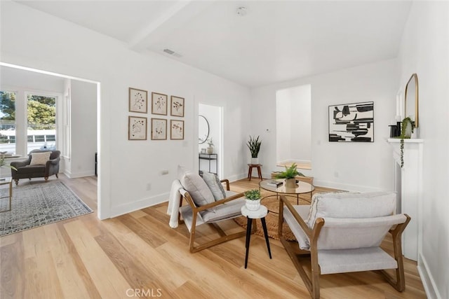 living area featuring light wood-type flooring and beamed ceiling