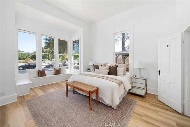 bedroom with multiple windows and light hardwood / wood-style flooring