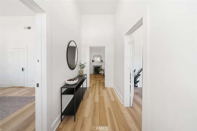 corridor featuring light wood-type flooring and a high ceiling