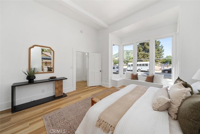 bedroom featuring light wood-type flooring and beam ceiling