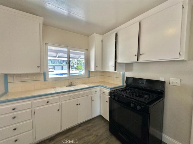 kitchen with white cabinetry, tasteful backsplash, dark wood-type flooring, black gas stove, and sink