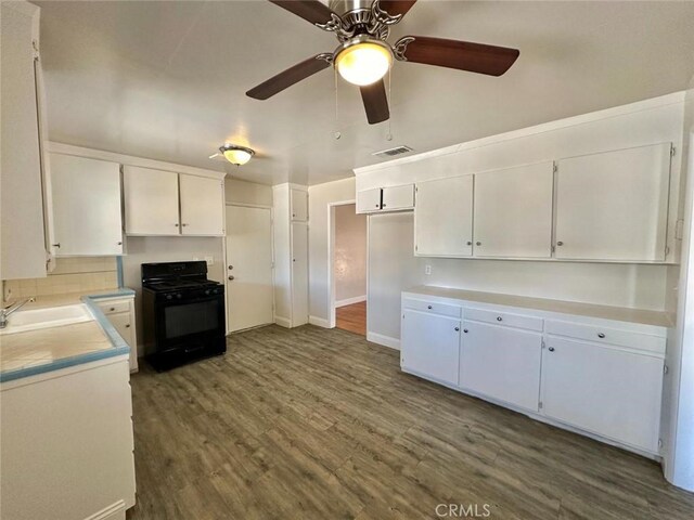 kitchen featuring ceiling fan, black gas range, sink, white cabinetry, and dark hardwood / wood-style flooring