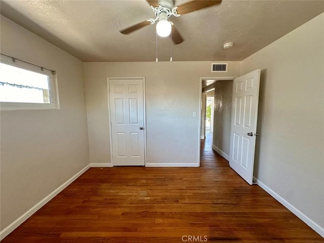 unfurnished bedroom featuring ceiling fan, a textured ceiling, dark hardwood / wood-style floors, and a closet