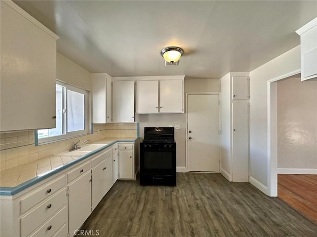 kitchen featuring tile counters, gas stove, white cabinets, and sink