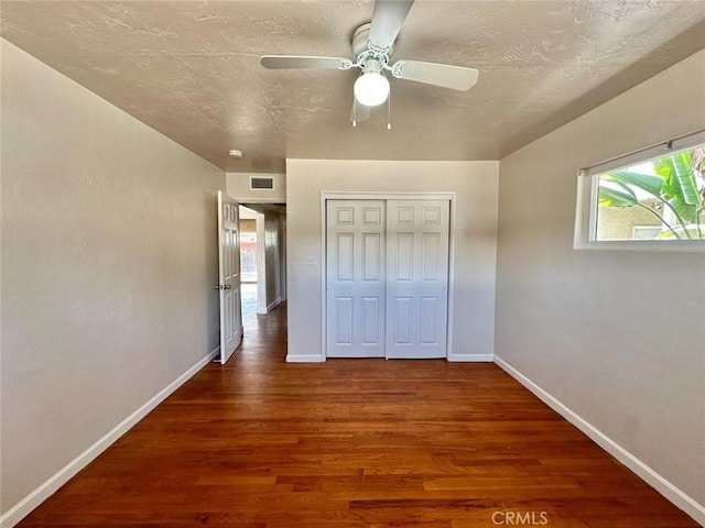 unfurnished bedroom featuring dark wood-type flooring, ceiling fan, a closet, and a textured ceiling