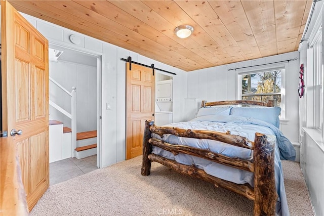 bedroom with a barn door, light colored carpet, and wooden ceiling