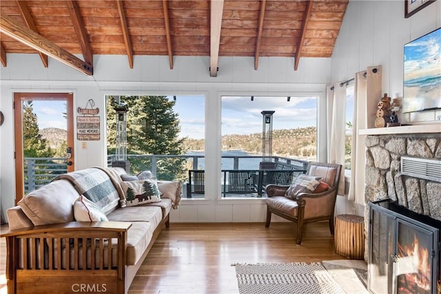 sunroom / solarium featuring wooden ceiling, vaulted ceiling with beams, and a stone fireplace