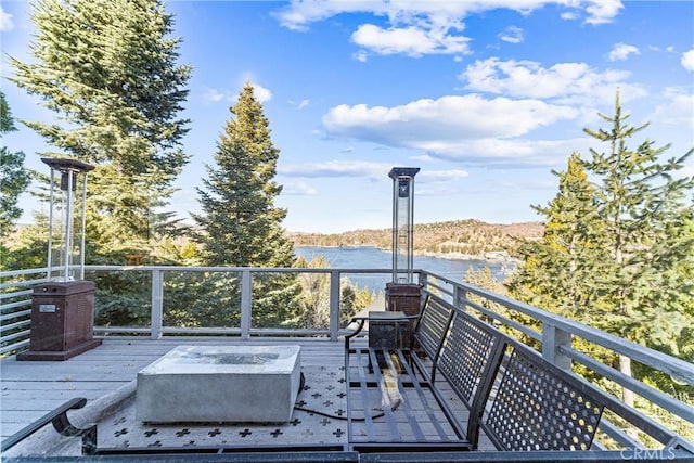 wooden terrace featuring a water view and a fire pit