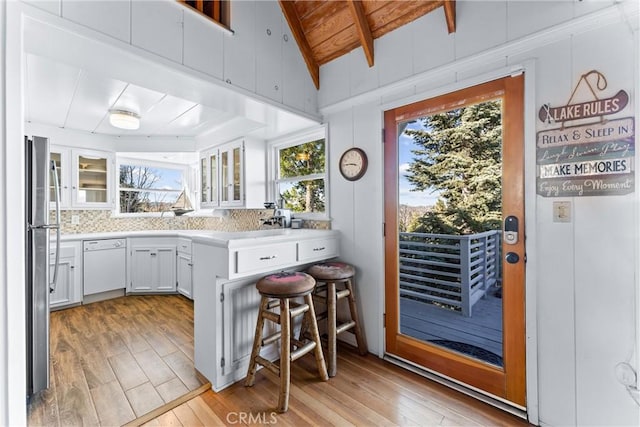 kitchen with white cabinetry, light hardwood / wood-style floors, dishwasher, stainless steel refrigerator, and a breakfast bar