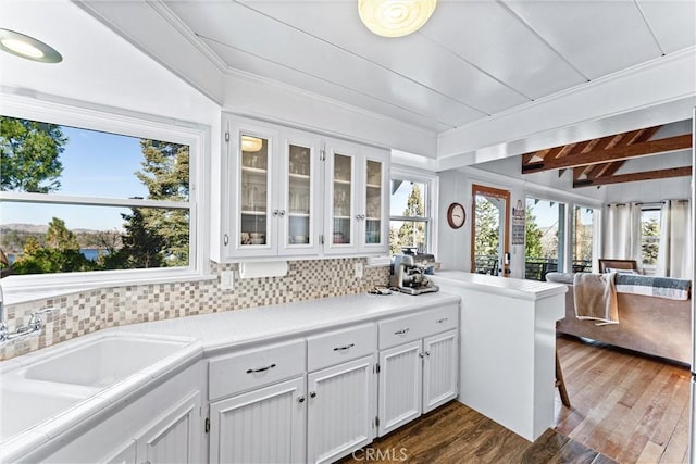 kitchen with dark wood-type flooring, white cabinetry, sink, backsplash, and lofted ceiling with beams