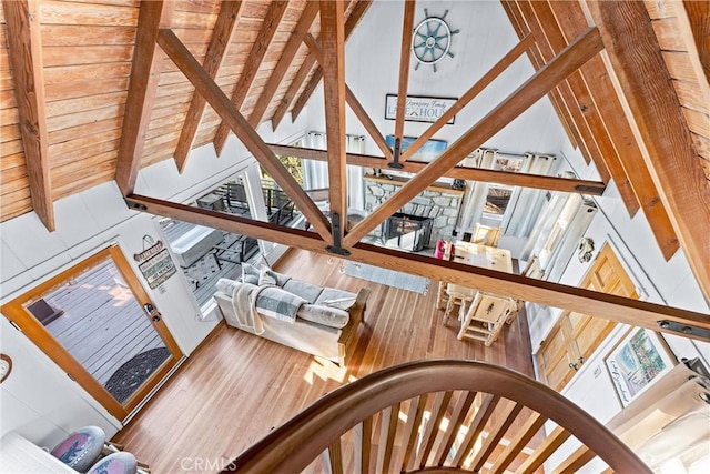 interior space featuring wood walls, beam ceiling, wood-type flooring, high vaulted ceiling, and wooden ceiling