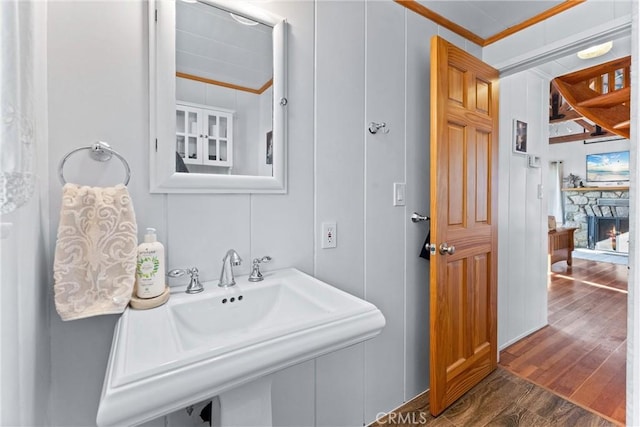 bathroom with a fireplace, sink, crown molding, and hardwood / wood-style floors