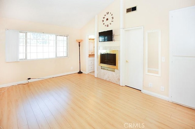 unfurnished living room with vaulted ceiling and light wood-type flooring