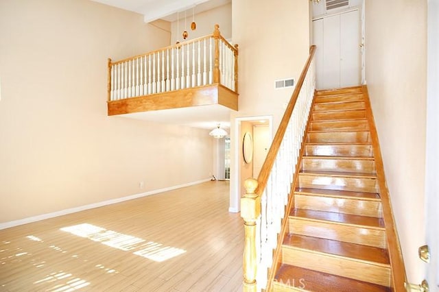 staircase featuring a towering ceiling and hardwood / wood-style floors