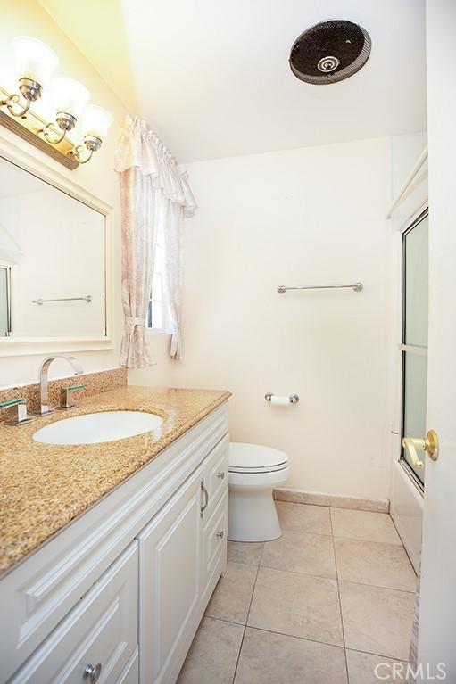 full bathroom with vanity, combined bath / shower with glass door, tile patterned floors, and toilet