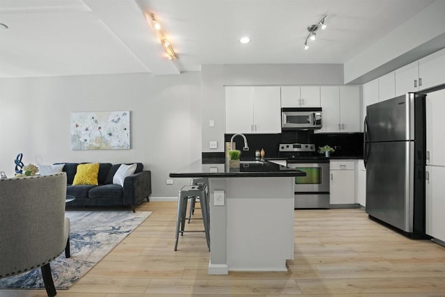 kitchen featuring stainless steel appliances, sink, white cabinetry, a kitchen bar, and kitchen peninsula