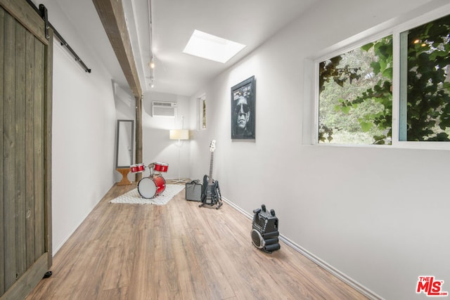 hallway featuring a skylight, a wall mounted AC, a barn door, and hardwood / wood-style flooring