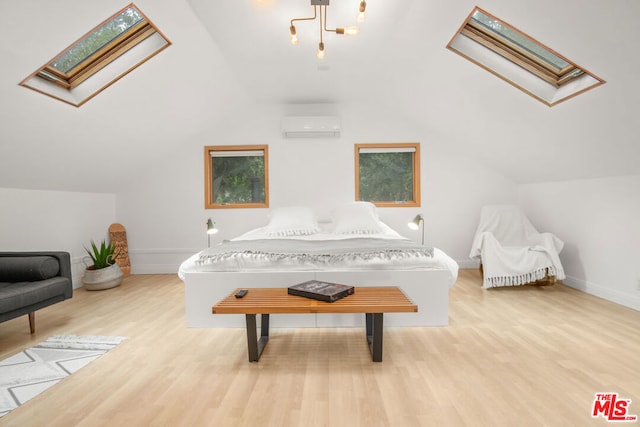 bedroom with light hardwood / wood-style floors, lofted ceiling with skylight, and a wall unit AC