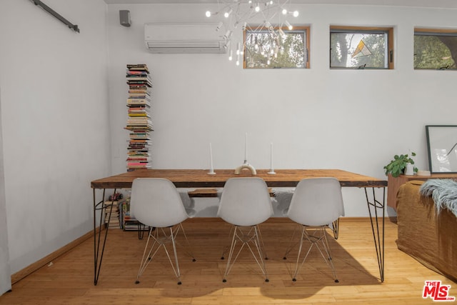 dining space featuring light hardwood / wood-style flooring, a wall mounted AC, and an inviting chandelier