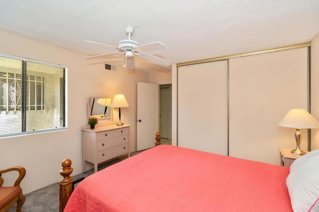 bedroom featuring ceiling fan, a closet, a textured ceiling, and carpet flooring