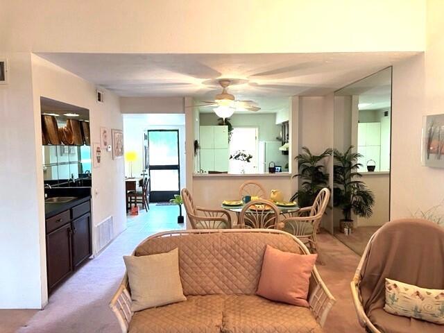 living room featuring light carpet, ceiling fan, and sink